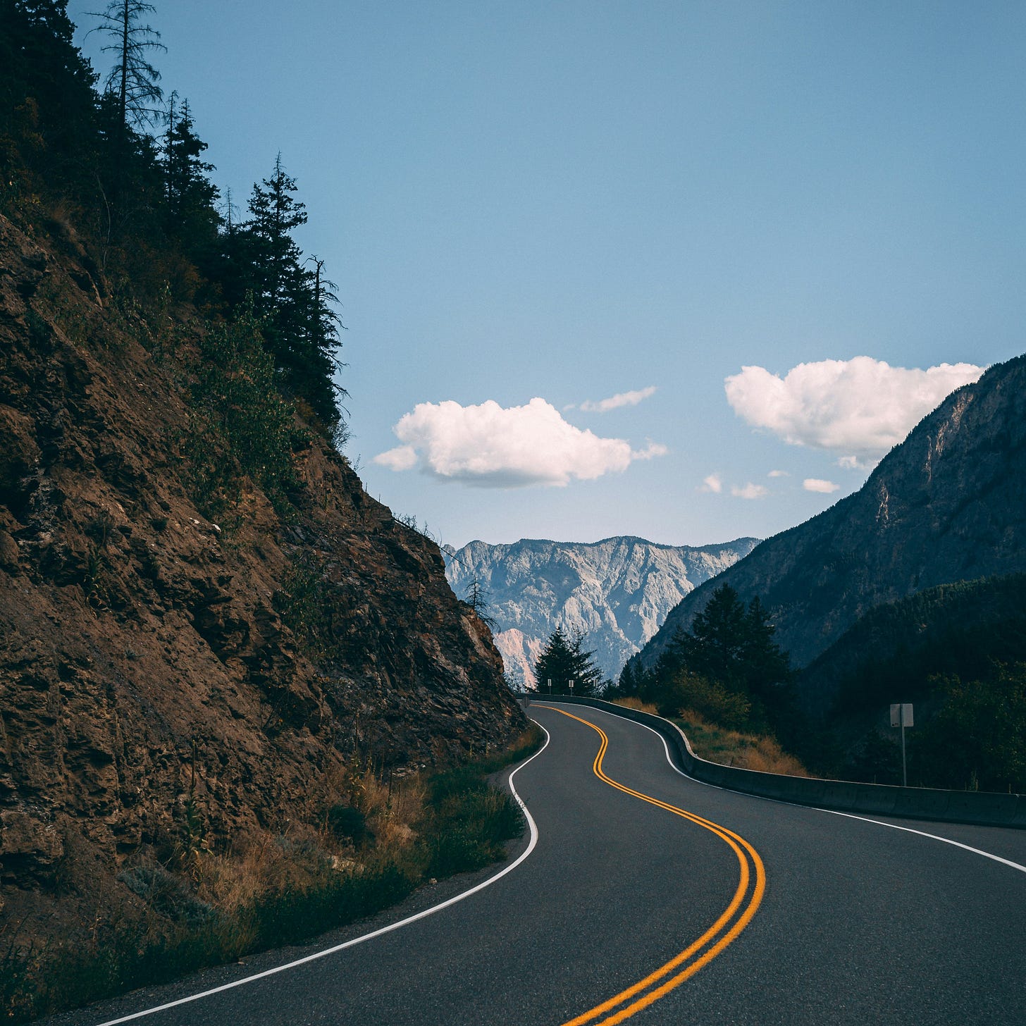 Winding highway with clear blue sky and crisp mountains in the distance